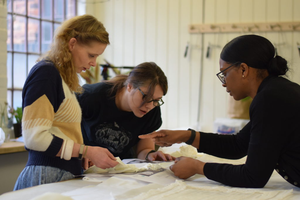 Three volunteers compare a shroud against catalogue images