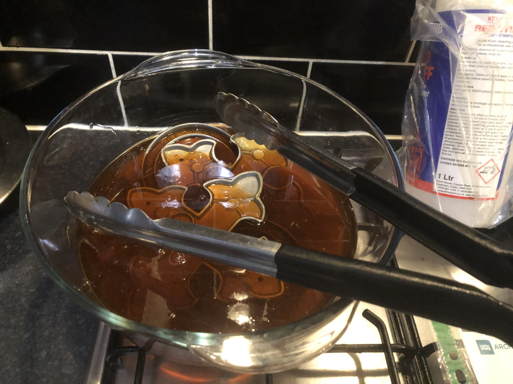 acid bath in a glass bowl, tongs in foreground.